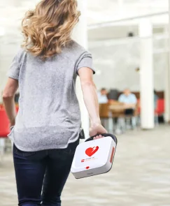 A woman carrying an automated external defibrillator to an emergency